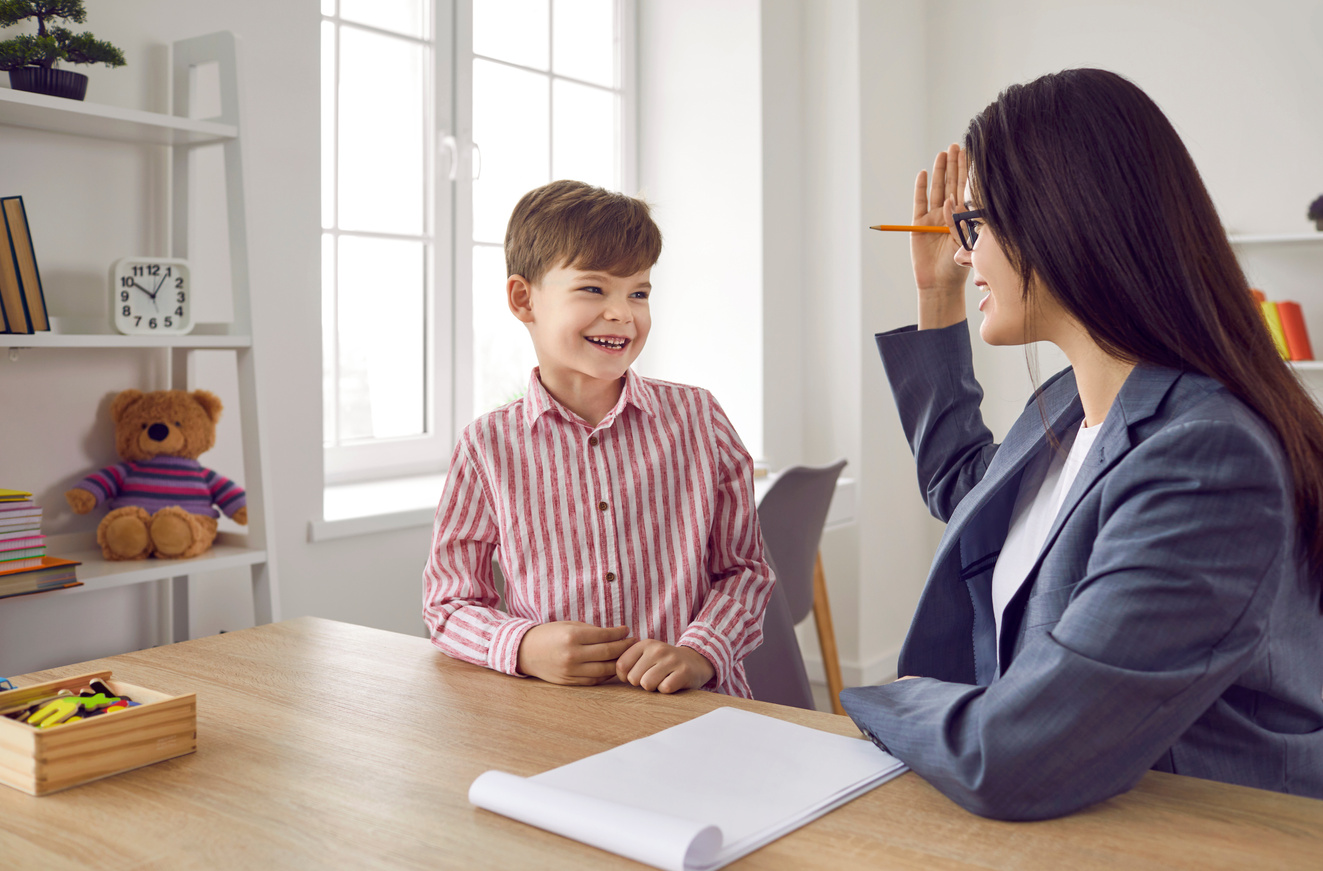 Friendly school counselor or psychologist communicating with a happy little child